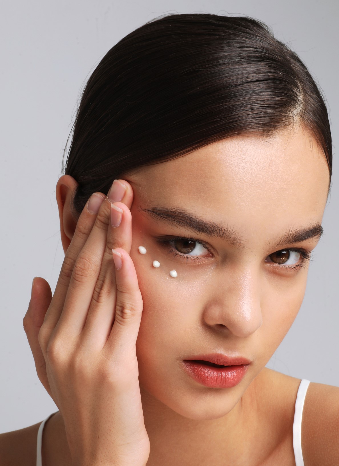 woman is applying an under-eye cream